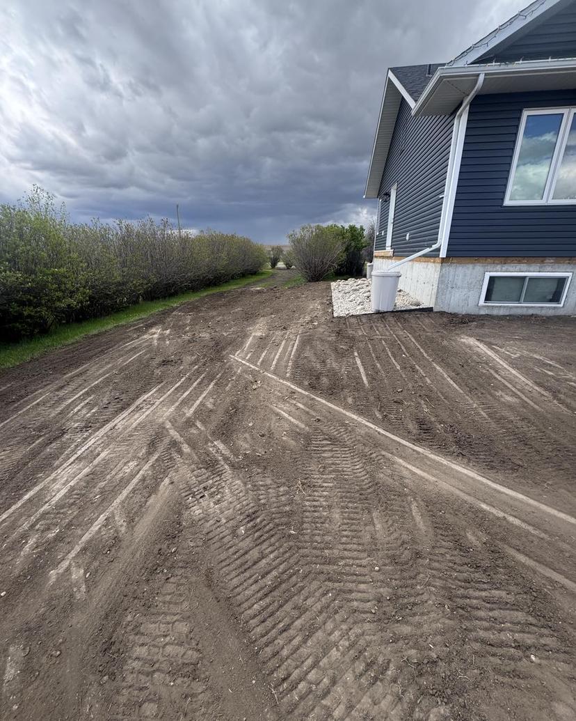 Professional site grading and drainage solutions in Strathmore - Bobcat skid steer creating proper water flow and level ground for residential and commercial properties